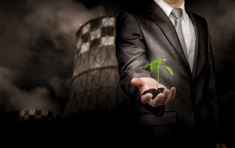 Businessman holding plant in front of industrial building