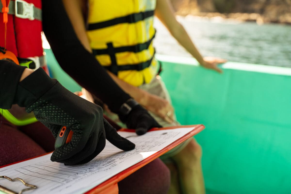 two marine biologists standing in a boat referencing notes