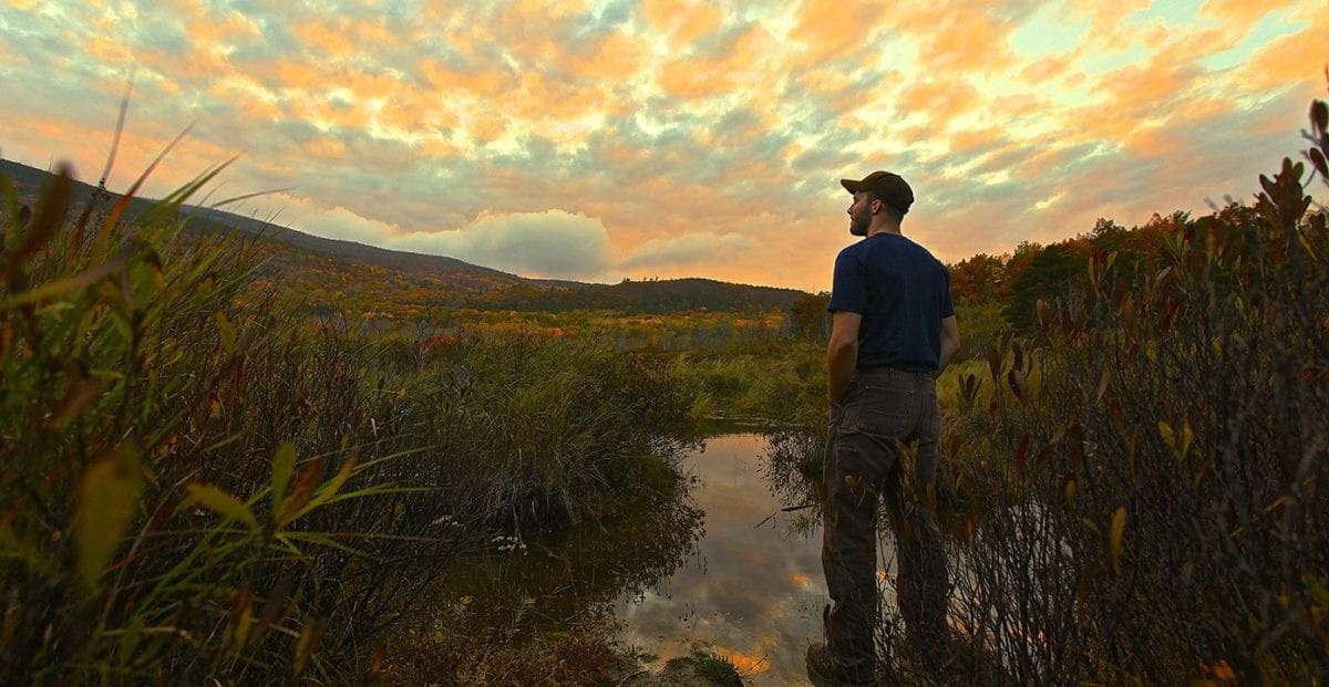 Man standing in wetland looking off into distance