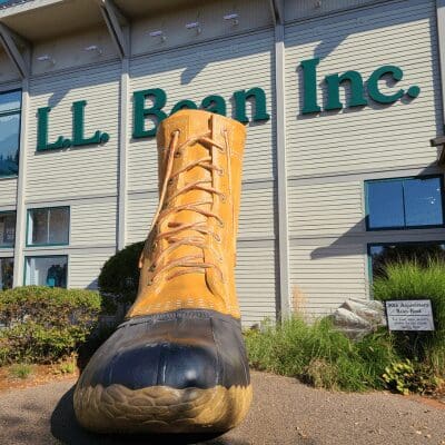 A large sculpture of a L.L. Bean rubber tipped rain and snow boot sits in front of the L.L. Bean sign.
