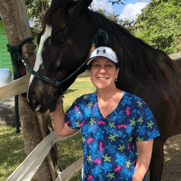 Dr. Elisa Bobrin smiles with a horse in a pasture.