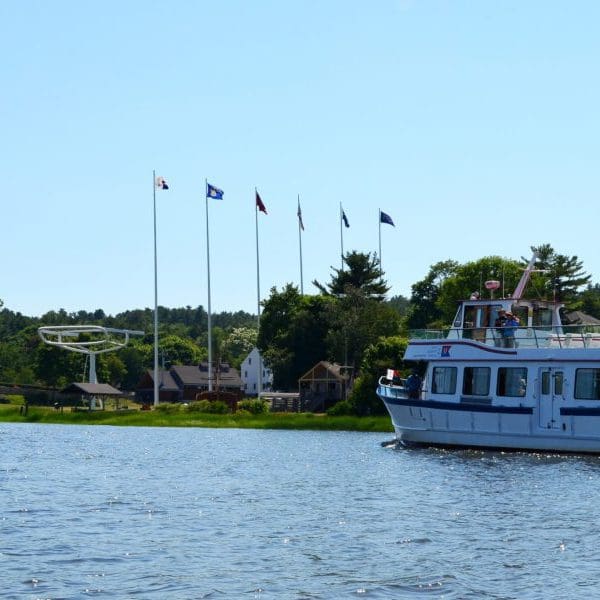 A tour boat floats down the river towards the Maritime Museum's outdoor exhibits on a sunny day.