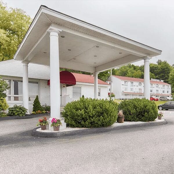A large white building with a red roof and overpass sits in a parking lot.
