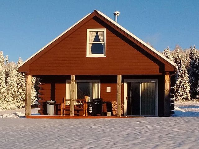 A bright red cabin sits in a snowy field is one of many possible accommodations at Sky Lodge. 
