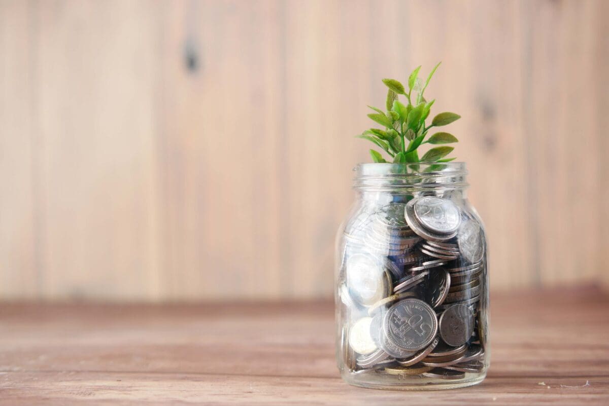 a jar of coins with a plant growing out of it showing economic growth with social mobility