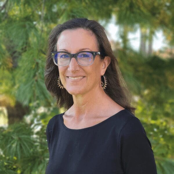 Dr. Kimberly Post smiles at the camera in front of a forest background.