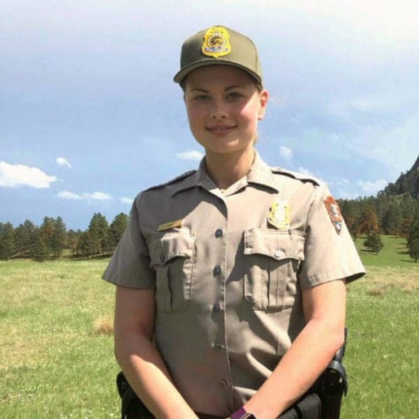 A conservation law student smiles in uniform in front of Devil's Tower.