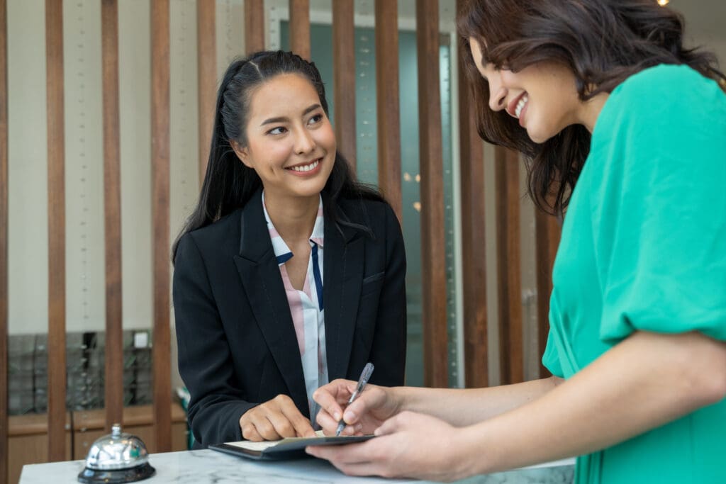 Check in hotel, Young woman checking in at counter with reception at hotel.