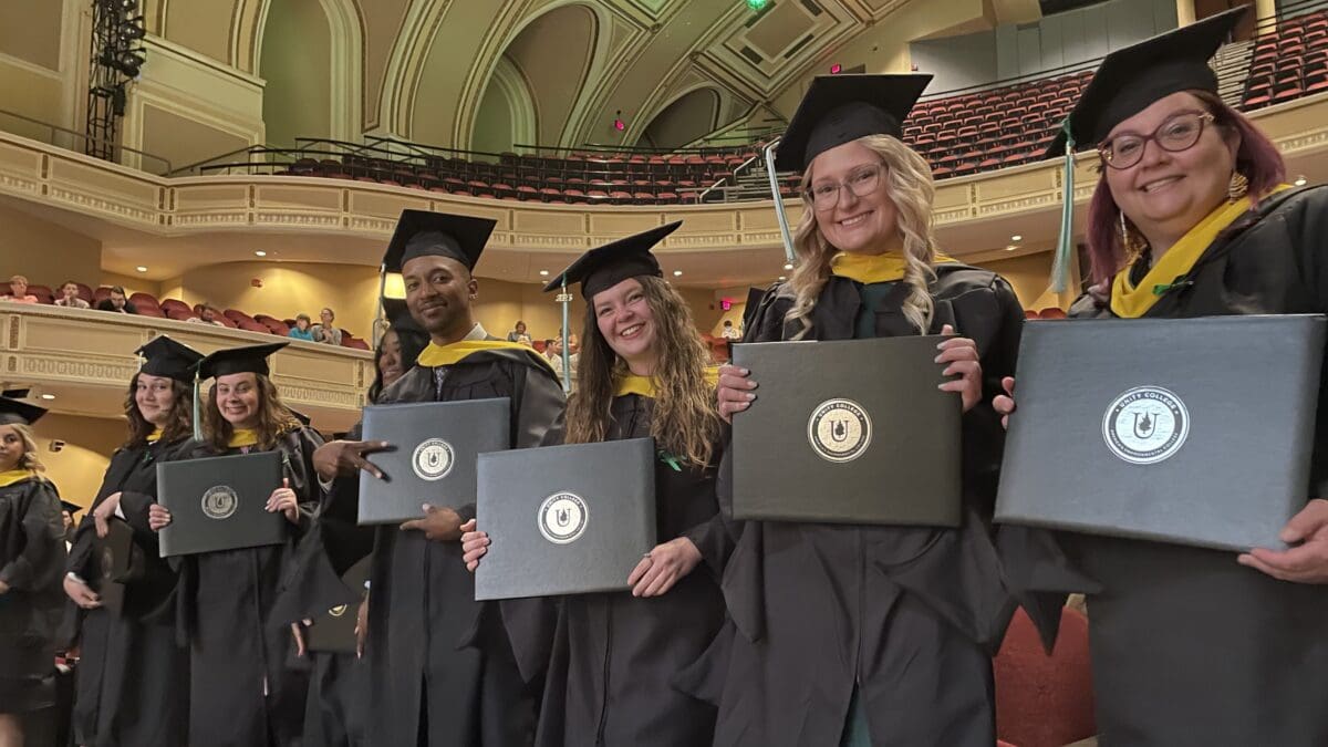 Students smile at the camera in their caps and gowns during Commencement.