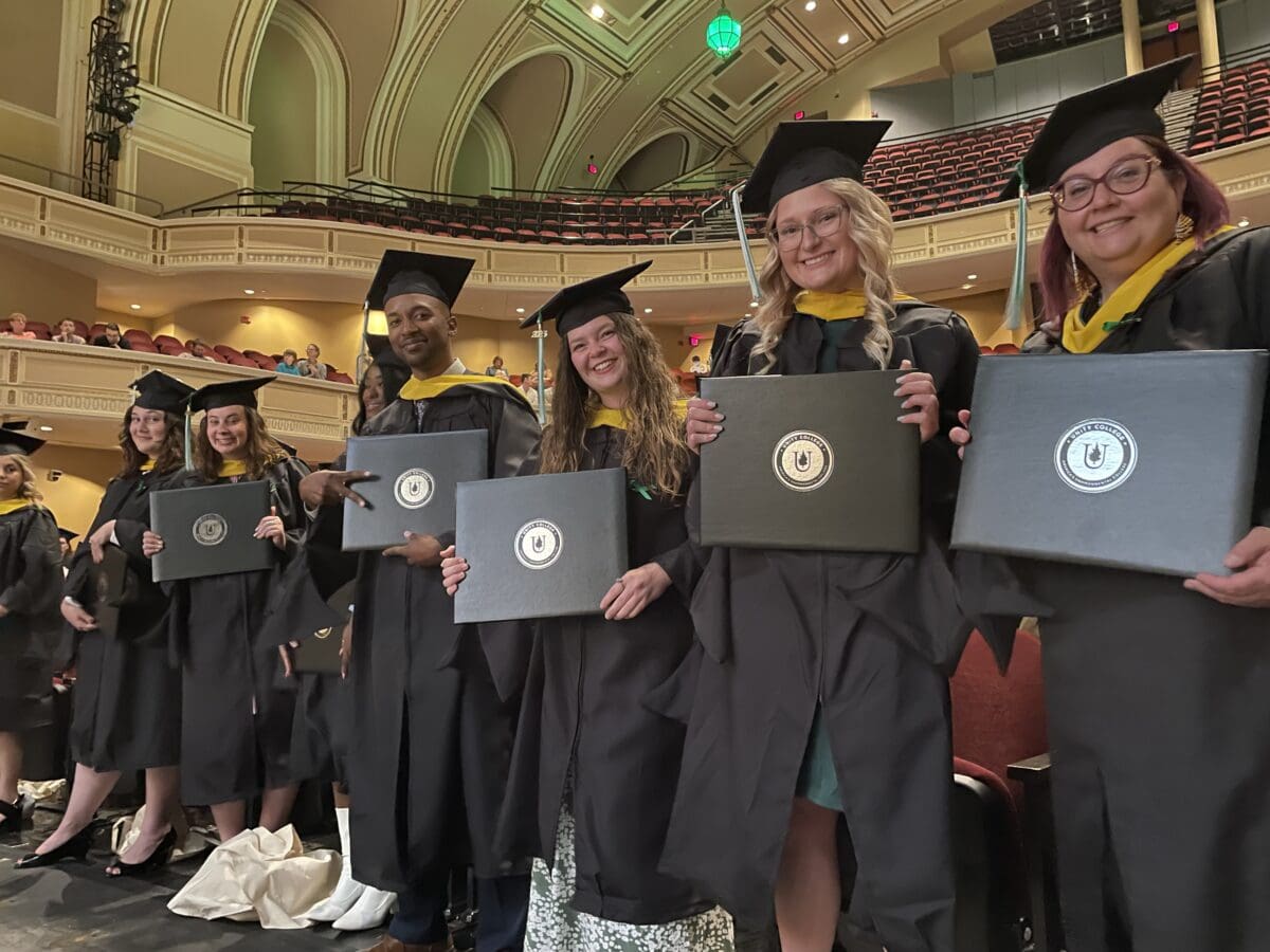 Students smile at the camera in their caps and gowns during Commencement.