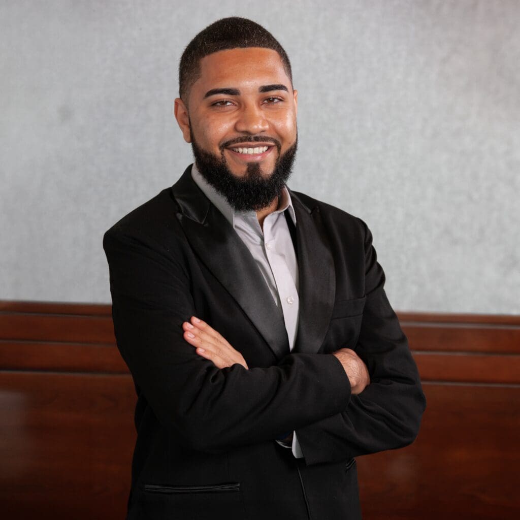 Juan smiles at the camera in a suit.