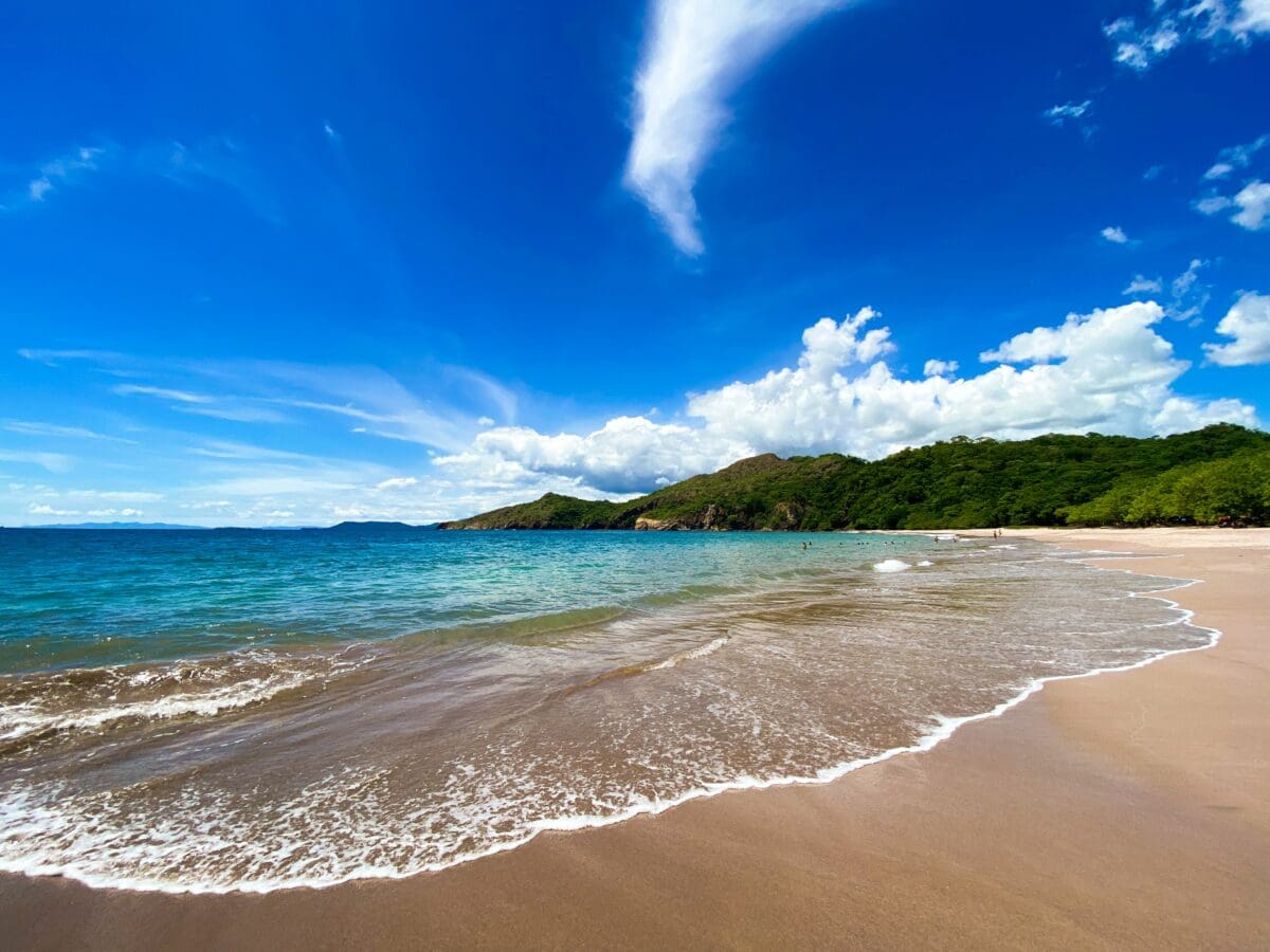 A sunny beach in the tropics with gentle waves on the shoreline. 