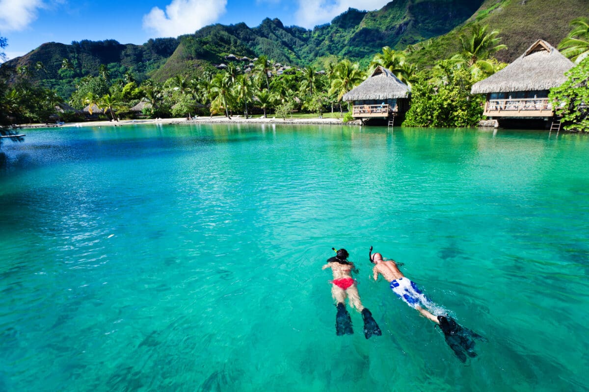 Young couple snorkeling in clean water over coral reef.