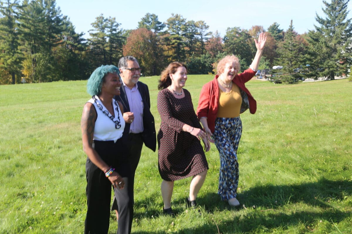 Four new staff members smile and joke around as they walk across Unity's Pineland campus.