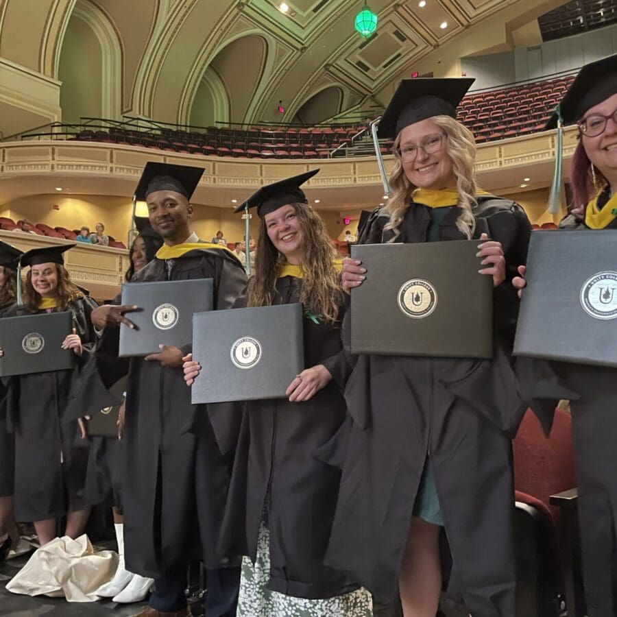 Students smile at the camera in their caps and gowns during Commencement.