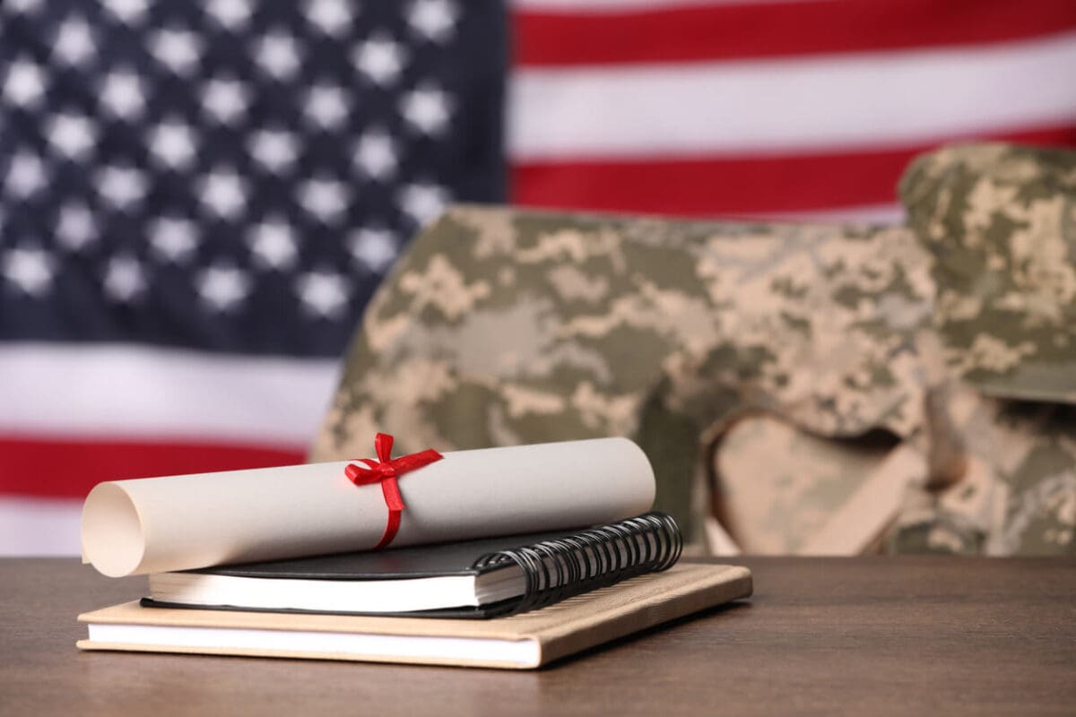 a military uniform on a chair by a college degree in front of an American flag