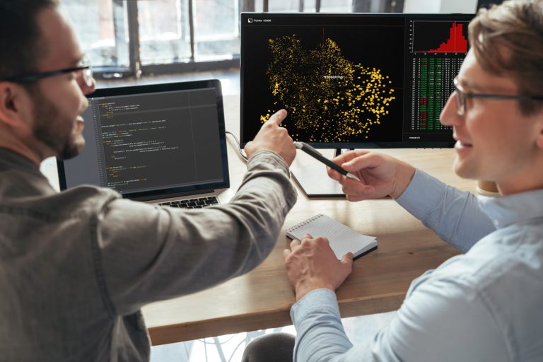 Two men discussing work in front of a computer.