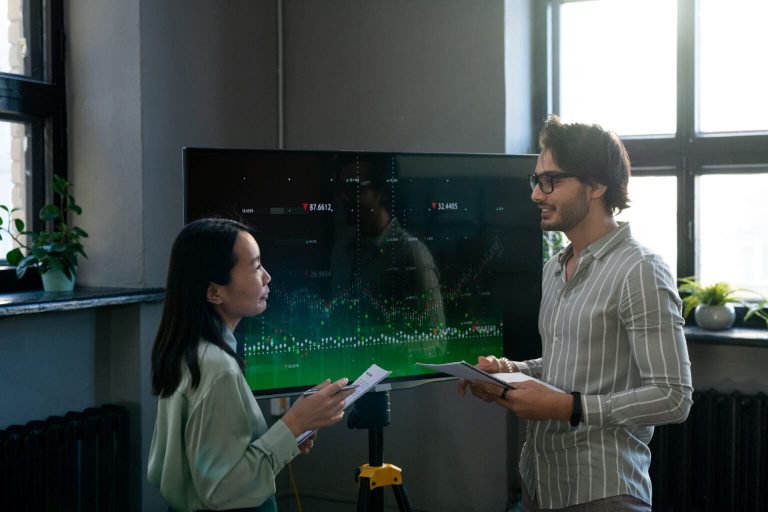 Two young confident analysts in front of a screen