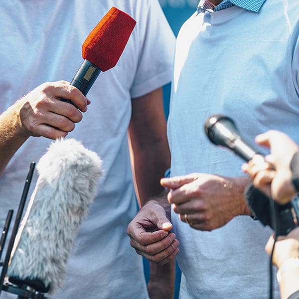 Media event with microphones pointed at a person.