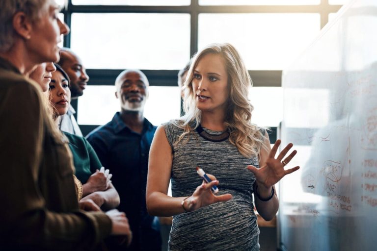 Picture of a woman presenting a topic to a group.