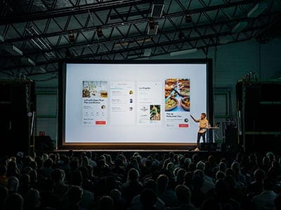 Woman standing on a stage giving a presentation.