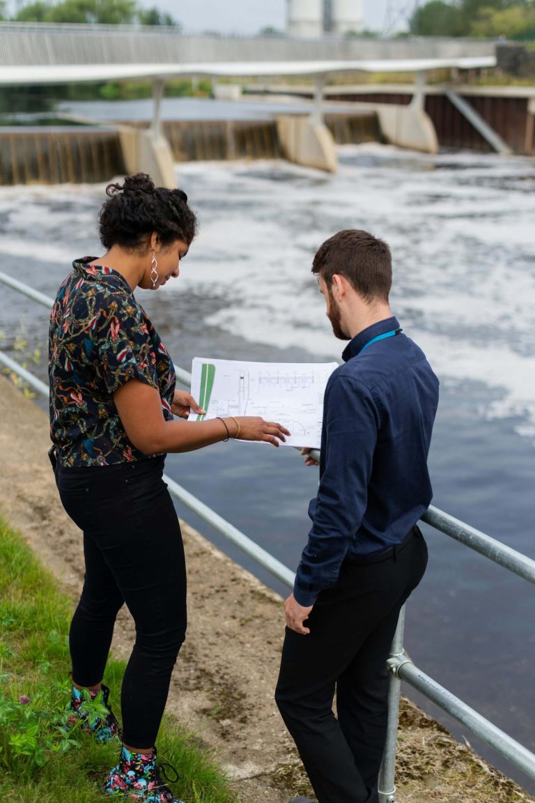2 engineers standing next to a water treatment facility.