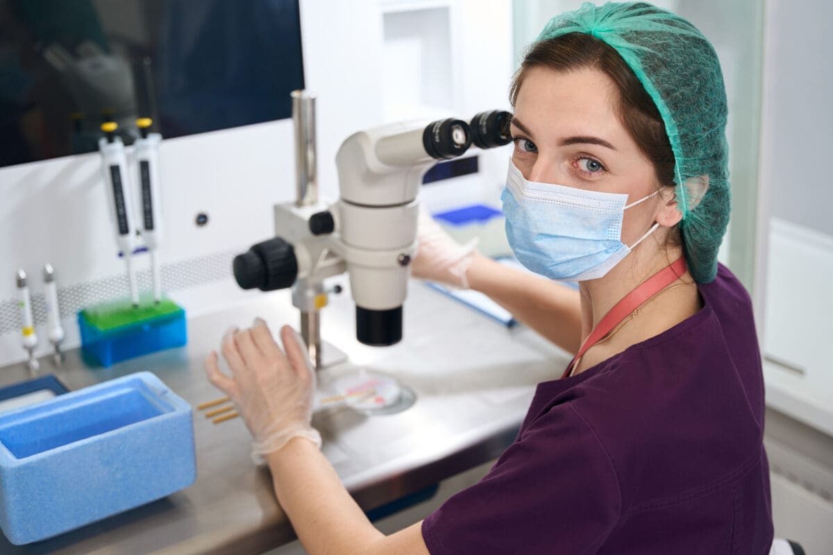 Woman at her workplace, next to a cuvette with liquid nitrogen, straws and modern equipment