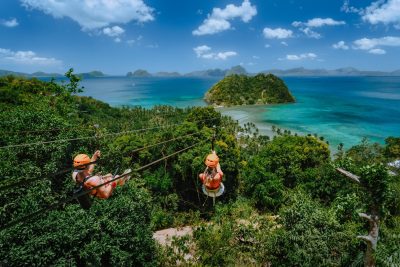 Zipline over Las Cabanas Beach with tourist on sunny day with white clouds over sea.