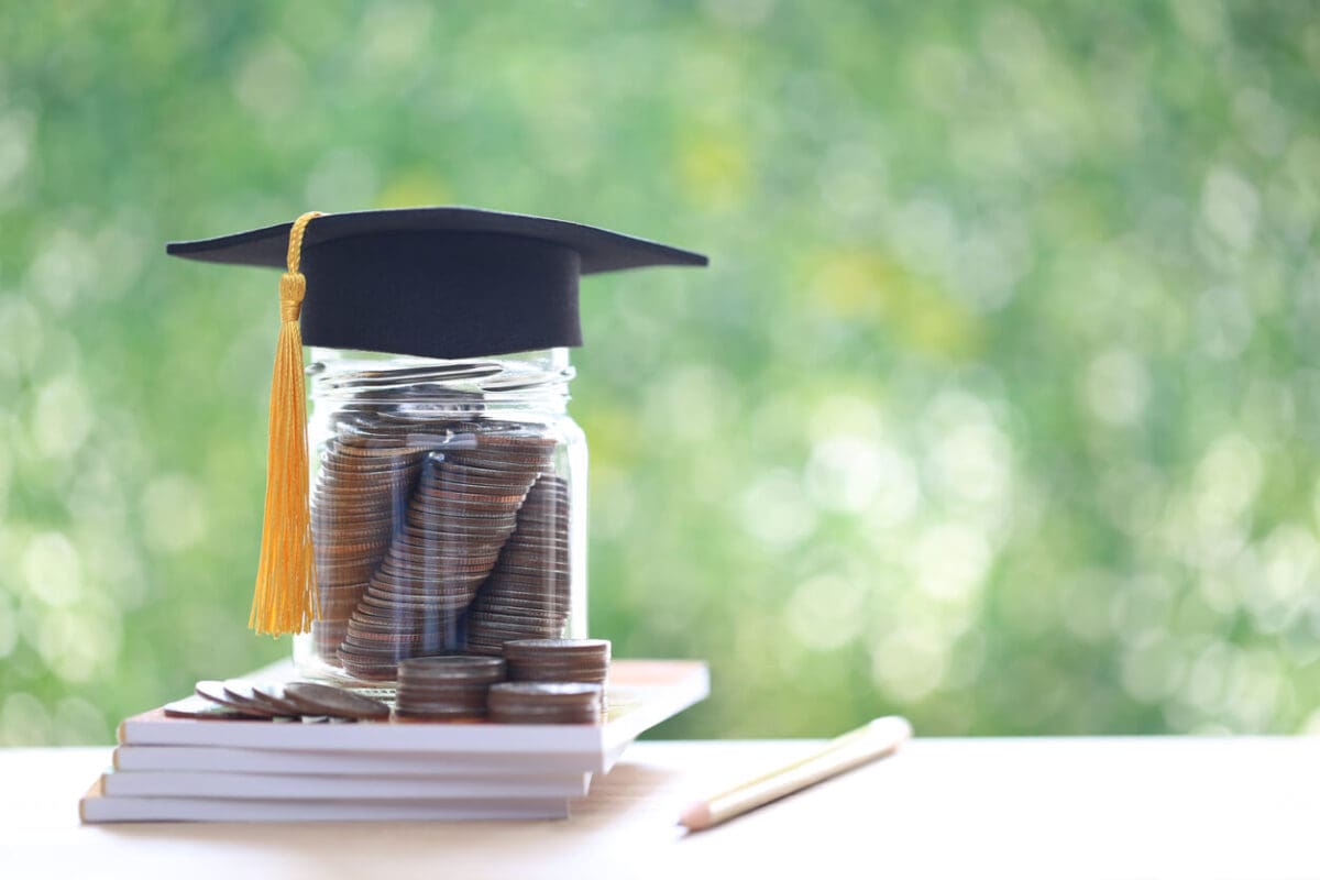 coins in a jar with a grad cap on top representing the cost of college