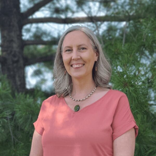 Dr. Michaeleen-Golay smiles at the camera in front of a forest background.