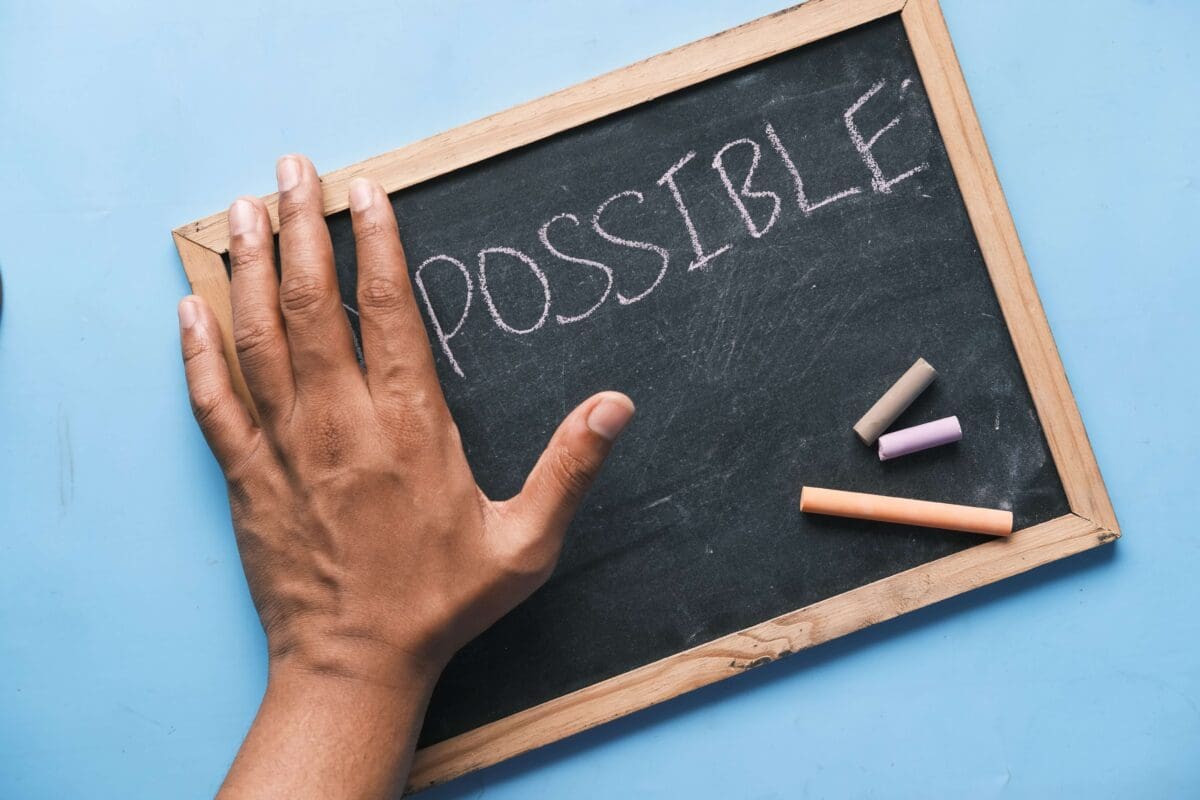 a sign that says impossible but a hand is covering the i and m to say possible