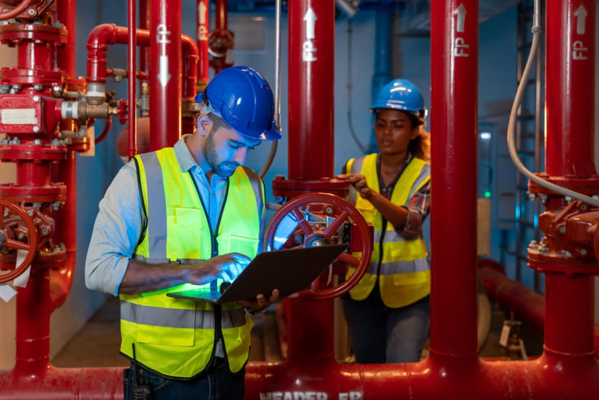 a fire protection engineer looking at his clipboard while standing by pipes