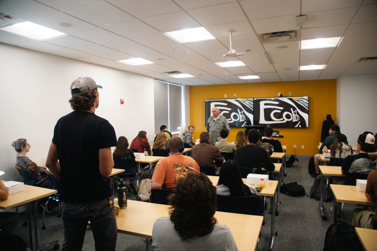 A student in a ball cap stands to ask Professor Van Hoven a question during the Q&A session.