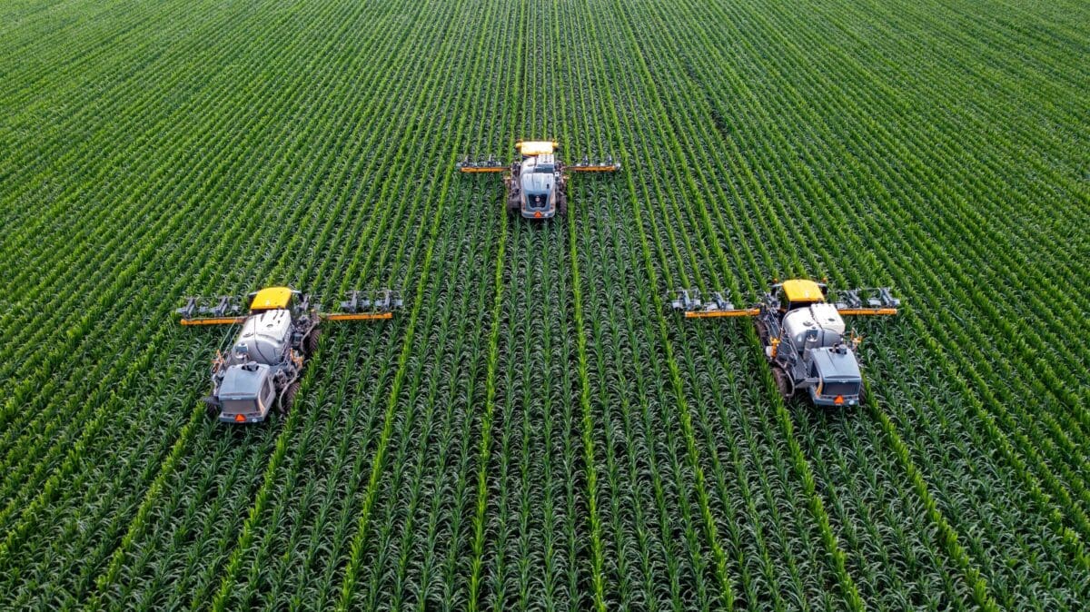 three tractors plowing a green field