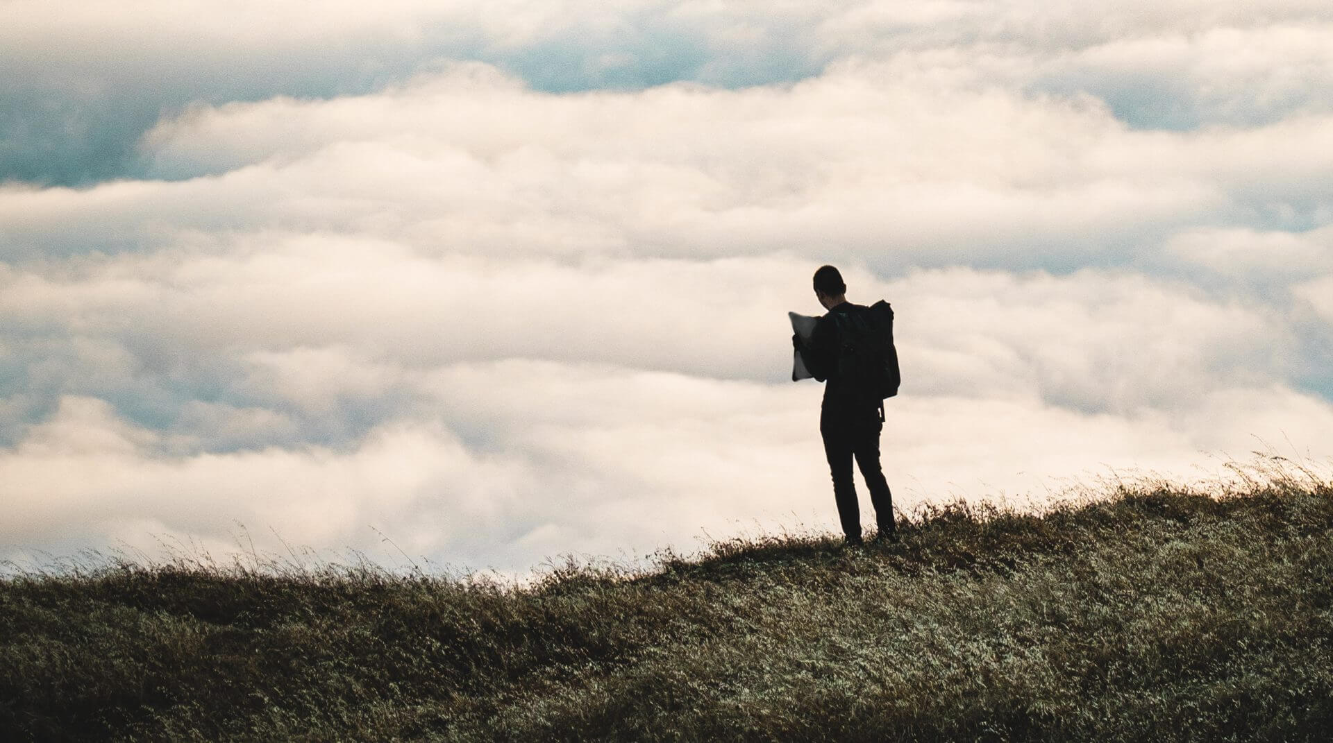 wide-silhouette-of-a-person-standing-on-a-grassy-hill-w-for-website.c