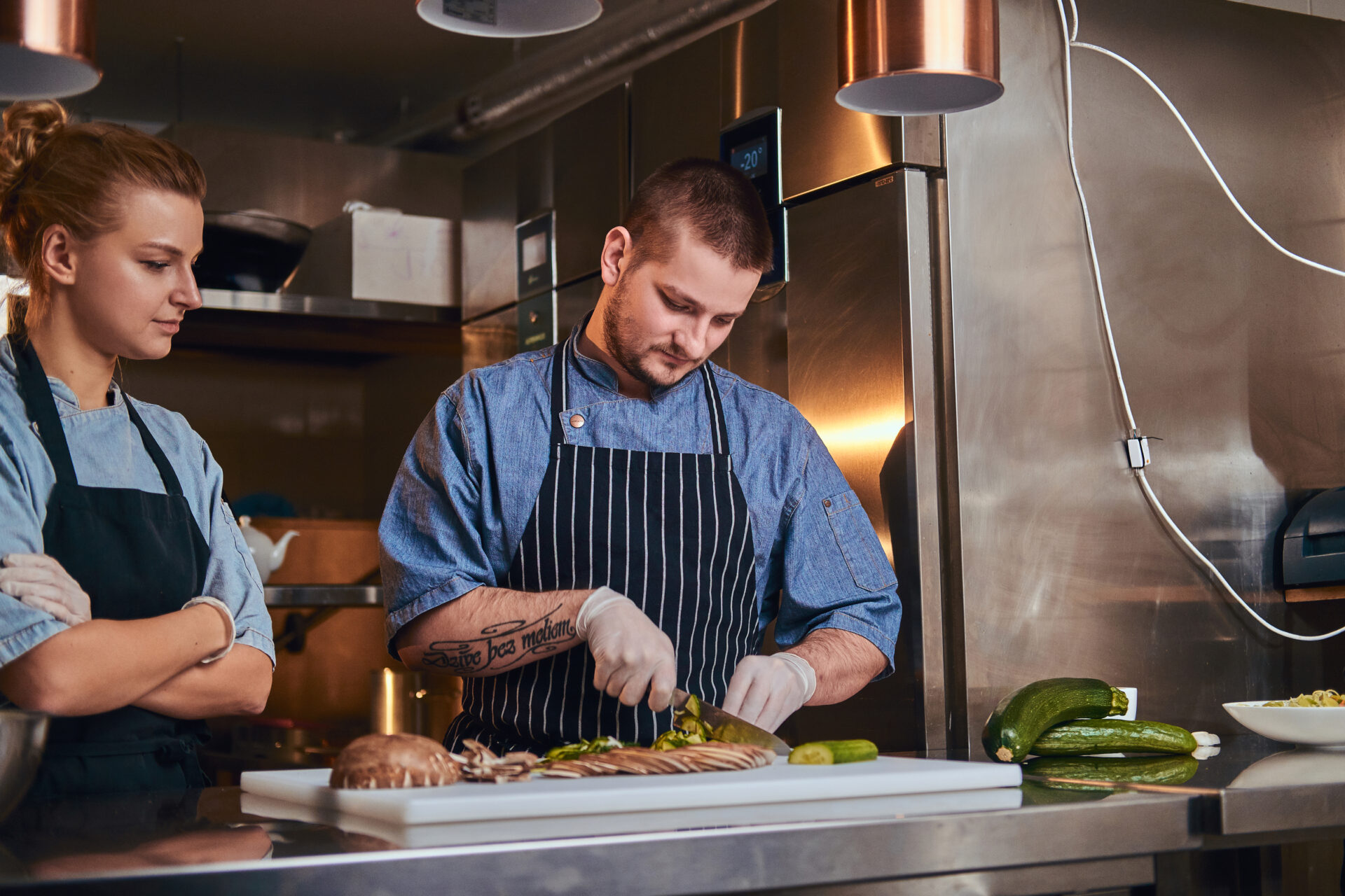 Male chef with assistant standing in a kitchen, preparing food in a luxury restaurant