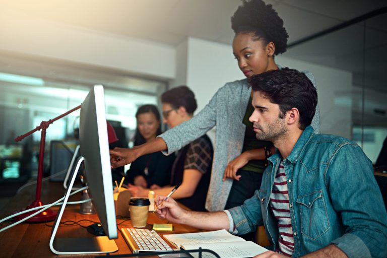 Woman helps a man at a computer screen.