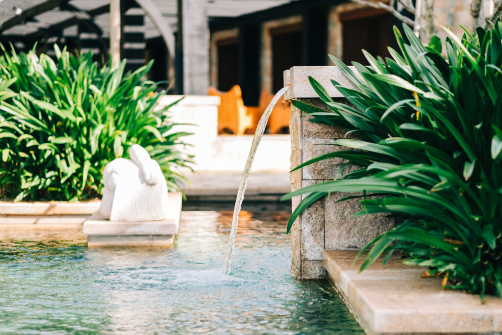 Turquoise water pool exterior in tropics with green vegetation. Sunny day