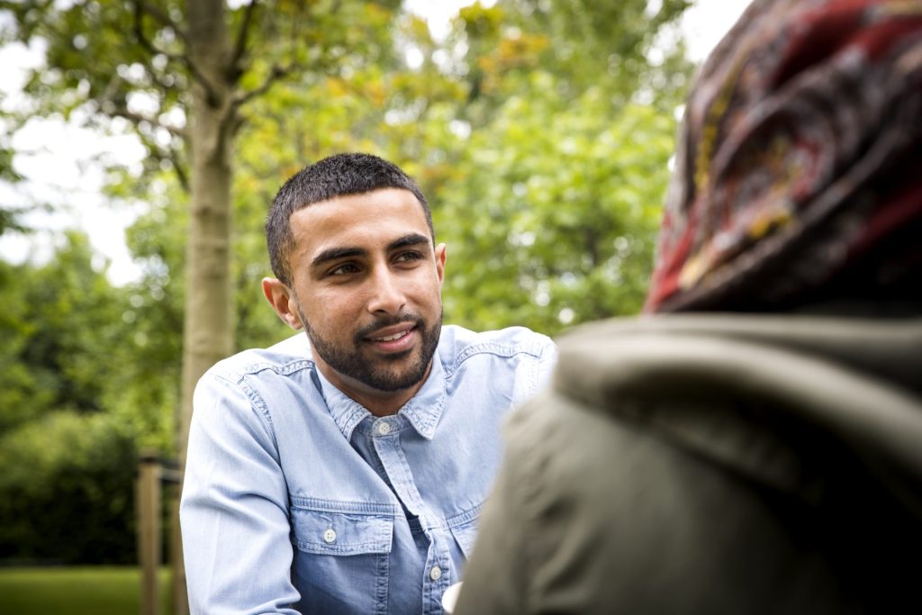 View over the shoulder of a man talking to a woman.