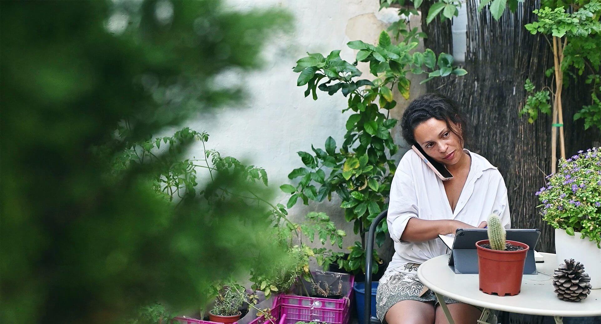 woman-working-on-a-tablet-in-a-serene-garden-setting-surrounded-by-lush-greenery
