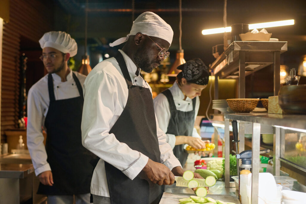 Young serious African American male cook chopping fresh zucchini