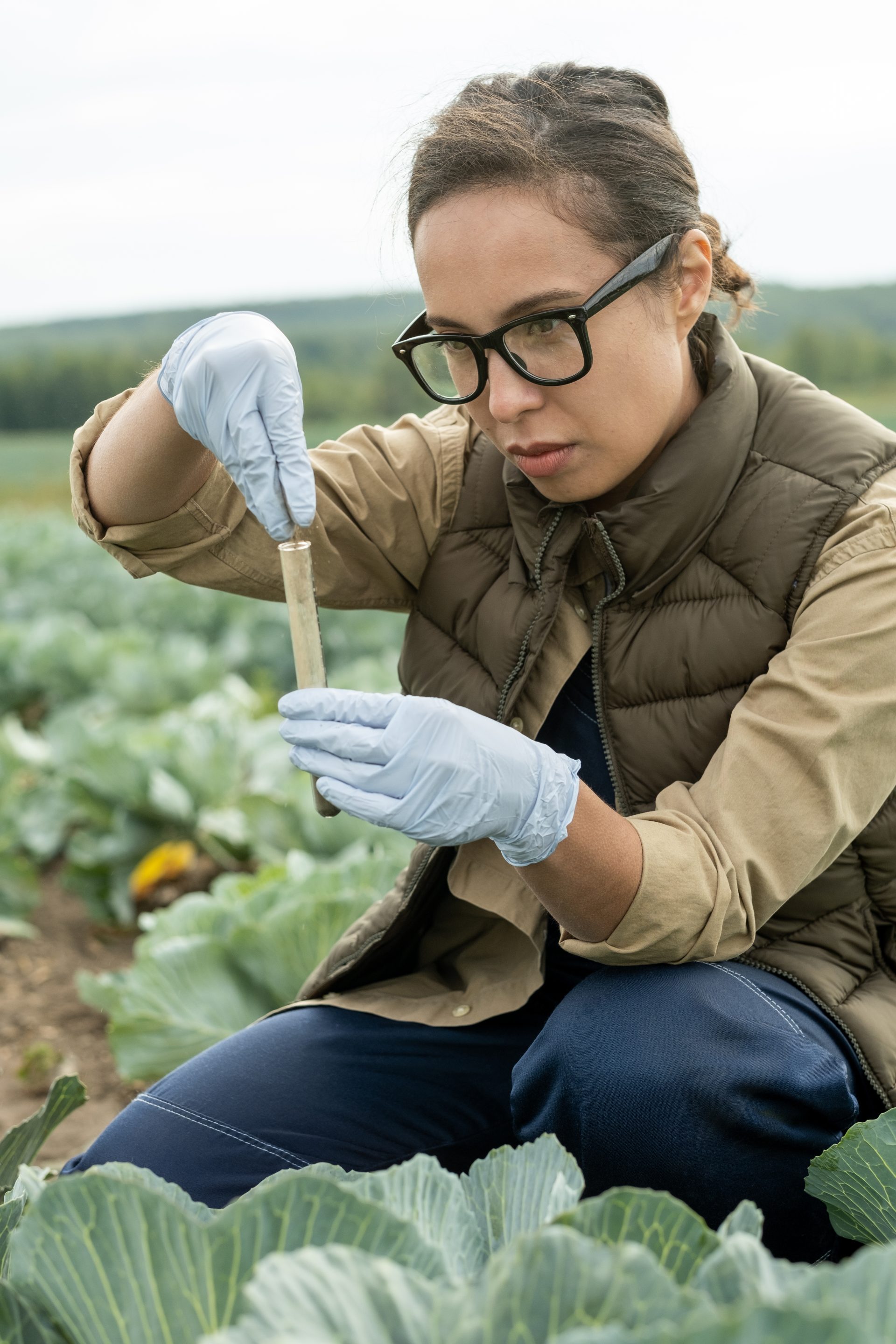serious-young-farmer-putting-soil-into-flask-2025-03-15-16-35-30-utc